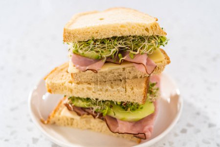 Foto de Stack of ham, cucumber, and sprout sandwiches on the white plate - Imagen libre de derechos