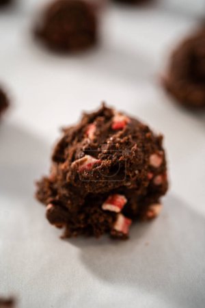 Téléchargez les photos : Ramasser la pâte à biscuits au chocolat avec une cuillère à pâte pour cuire des biscuits au chocolat avec des pépites de menthe poivrée. - en image libre de droit
