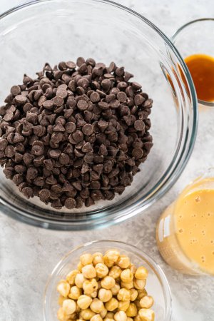 Téléchargez les photos : Ingrédients mesurés dans des bols à mélanger en verre pour préparer le chocolat noisette caramel. - en image libre de droit