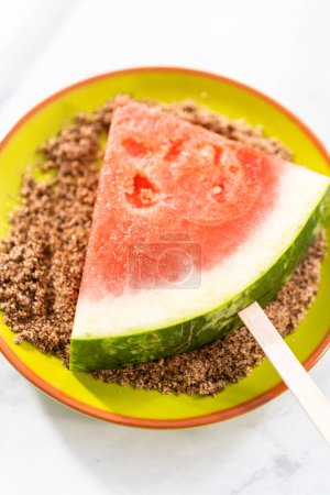 Photo for Dipping watermelon pops into the chili lime salt to prepare Mexican watermelon pops. - Royalty Free Image