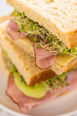 Photo for Stack of ham, cucumber, and sprout sandwiches on the white plate - Royalty Free Image