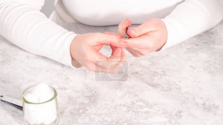 Foto de Mujer terminando su manicura en casa con simples herramientas de manicura. Cortar las cutículas alrededor de las uñas. - Imagen libre de derechos