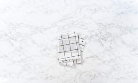 Foto de Toalla de cocina plegada sobre una superficie de mármol. - Imagen libre de derechos