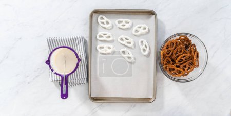 Foto de Flat lay. Dipping pretzels twists into melted chocolate to make chocolate-covered pretzel twists. - Imagen libre de derechos