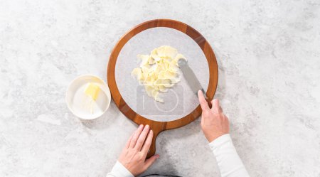 Foto de Flat lay. Assembling butter board with vegetables and bread on a round wood cutting board. - Imagen libre de derechos