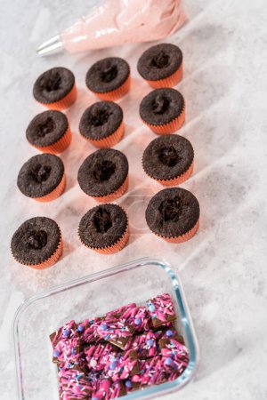 Téléchargez les photos : Glaçage à la crème au beurre à la fraise sur des cupcakes au chocolat. - en image libre de droit