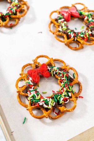 Photo for Dipping pretzels twists into melted chocolate to make a chocolate pretzel Christmas wreath. - Royalty Free Image