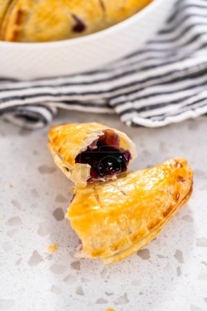 Photo for Freshly baked sweet empanadas with blueberries on the kitchen counter. - Royalty Free Image