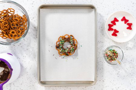 Photo for Flat lay. Dipping pretzels twists into melted chocolate to make a chocolate pretzel Christmas wreath. - Royalty Free Image
