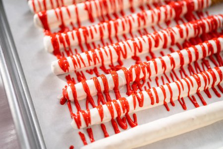 Photo for Drizzling melted chocolate over chocolate-dipped pretzels rods and decorating with sprinkles to make chocolate-covered pretzel rods for Valentines Day. - Royalty Free Image