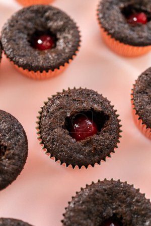 Téléchargez les photos : Remplissage de cupcakes au chocolat fraîchement cuits avec remplissage aux fraises. - en image libre de droit