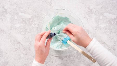 Photo for Flat lay. Step by step. Mixing in blue food coloring into the buttercream frosting. - Royalty Free Image