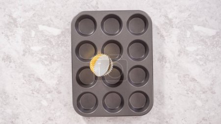 Photo for Flat lay. Step by step. Lining cupcake baking pan with foil cupcake liners to bake unicorn rainbow chocolate cupcakes. - Royalty Free Image