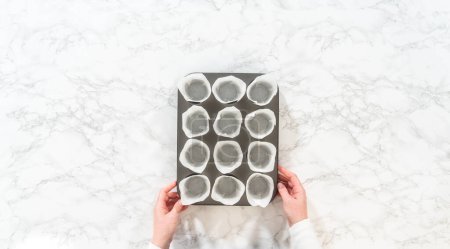 Téléchargez les photos : Pose plate. Doublure plaque de cuisson cupcake avec doublures de tulipes en papier pour cuire sans levure cupcakes rouleau de cannelle. - en image libre de droit