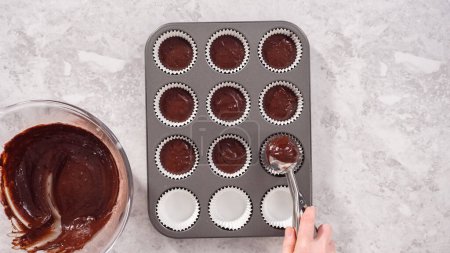 Téléchargez les photos : Pose plate. Pas à pas. Ramasser la pâte de cupcake au chocolat dans les doublures de cupcake. - en image libre de droit