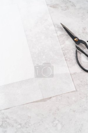 Photo for Lining square cheesecake pan with parchment paper sheet to prepare eggnog fudge. - Royalty Free Image