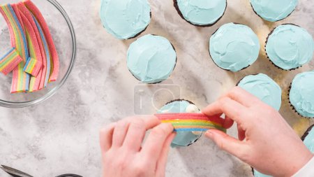 Foto de Acostado. Paso a paso. Decoración de cupcakes de chocolate con glaseado de crema de mantequilla y dulces de arco iris. - Imagen libre de derechos