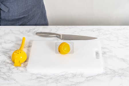 Photo for Zesting and juicing fresh lemon on a white cutting board. - Royalty Free Image