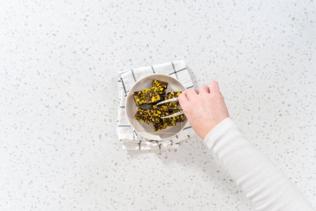 Téléchargez les photos : Flat lay. Homemade chocolate pistachio fudge square pieces on a white plate. - en image libre de droit