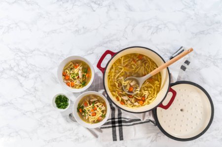 Photo for Flat lay. Serving chicken noodle soup with kluski noodles in white ceramic soup bowls. - Royalty Free Image
