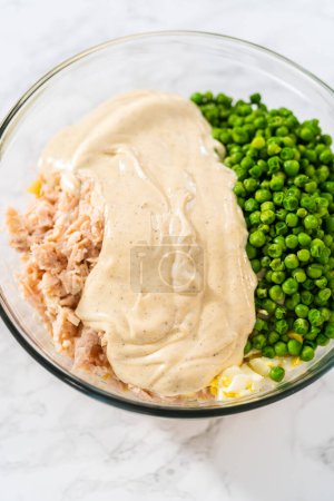Téléchargez les photos : Mélanger les ingrédients dans un grand bol à mélanger en verre pour faire une salade de macaronis avec du poulet. - en image libre de droit