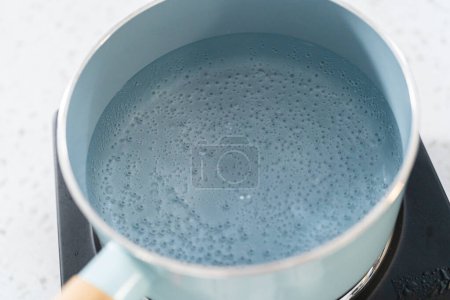 Téléchargez les photos : Boiling water in a cooking pot to prepare chocolate pistachio fudge. - en image libre de droit