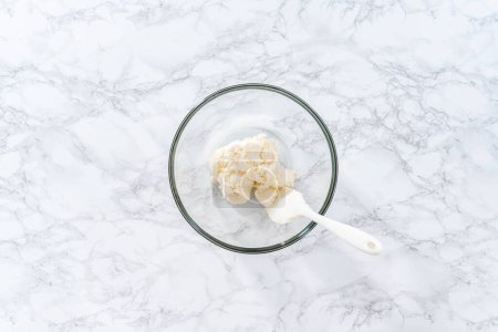 Téléchargez les photos : Pose plate. Mélange de glaçage à la vanille acheté en magasin dans un bol en verre mélangé avec un mélangeur à main. - en image libre de droit