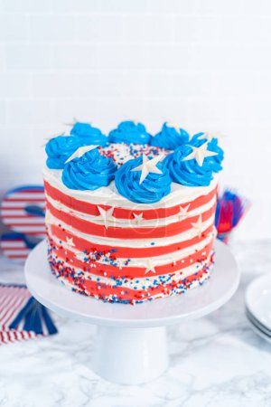 Photo for Decorating chocolate cake with white, red, and blue buttercream frosting for July 4th celebration. - Royalty Free Image