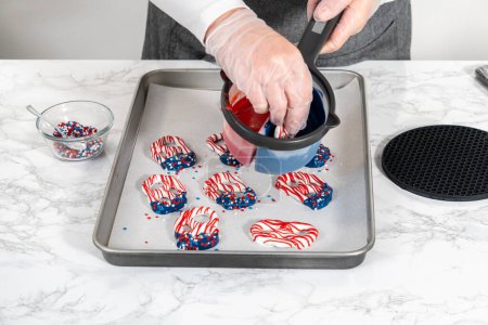 Photo for Flat lay. Dipping pretzels twists into melted chocolate to make red, white, and blue chocolate-covered pretzel twists. - Royalty Free Image
