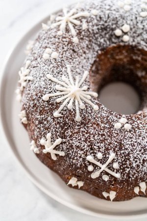 Foto de Gingerbread bundt cake with caramel filling, buttercream frosting, and powdered sugar dusting on the kitchen counter. - Imagen libre de derechos