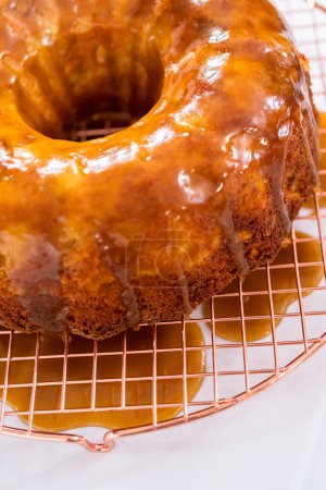 Photo for Pouring homemade caramel glaze over freshly baked apple bundt cake. - Royalty Free Image