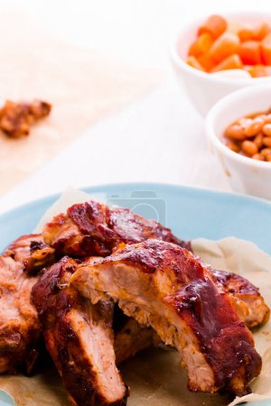Photo for Baby back ribs on the plate with baked beand and fried carrots. - Royalty Free Image