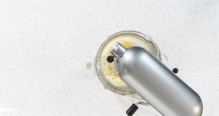 Foto de Acostado. Azotar los ingredientes en una batidora eléctrica para hacer glaseado de crema de mantequilla dulce de leche. - Imagen libre de derechos