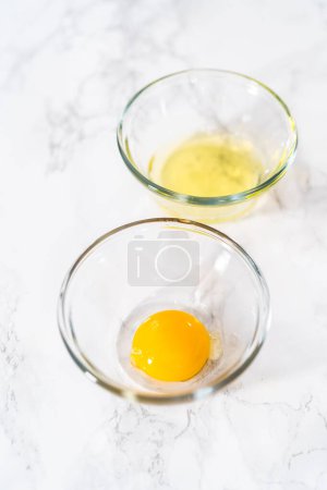 Foto de Separar las claras de huevo y las yemas de huevo en tazones pequeños. - Imagen libre de derechos