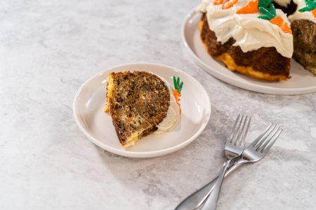 Téléchargez les photos : Trancher le gâteau bundt aux carottes fraîchement cuit avec glaçage au fromage à la crème et garnitures décorées de gâteau aux carottes au chocolat. - en image libre de droit