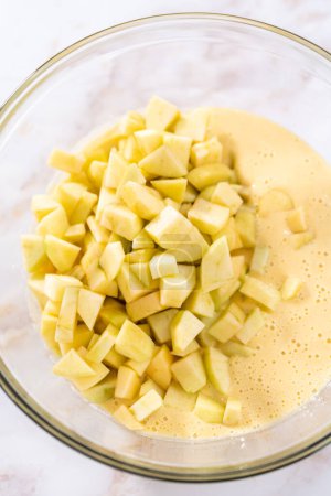 Téléchargez les photos : Mélanger les ingrédients dans un grand bol à mélanger en verre pour cuire le muffin sharlotka aux pommes. - en image libre de droit