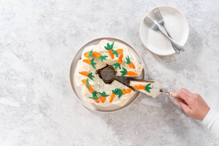 Téléchargez les photos : Pose plate. Trancher le gâteau bundt aux carottes fraîchement cuit avec glaçage au fromage à la crème et garnitures décorées de gâteau aux carottes au chocolat. - en image libre de droit