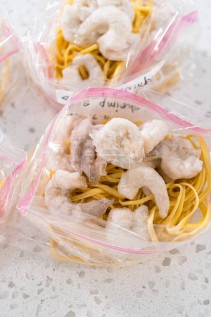 Téléchargez les photos : Emballage maison crevettes congelées préparation de repas scampi dans des sacs refermables en plastique. - en image libre de droit