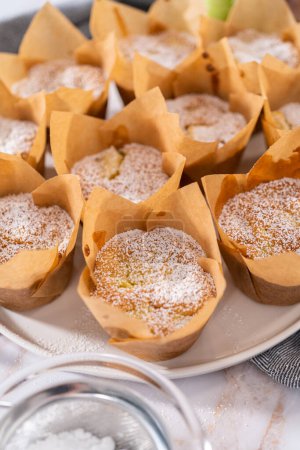 Photo for Garnishing freshly baked apple sharlotka muffin dusted with powdered sugar. - Royalty Free Image