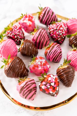 Foto de Fresas cubiertas de chocolate gourmet decoradas con lloviznas de chocolate y espolvoreos en un plato blanco. - Imagen libre de derechos