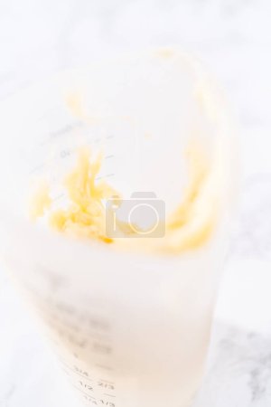 Photo for Cream cheese drizzle sauce in a silicone measuring cup. - Royalty Free Image