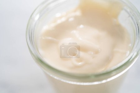 Téléchargez les photos : Glaçure au fromage à la crème dans un petit pot en verre. - en image libre de droit