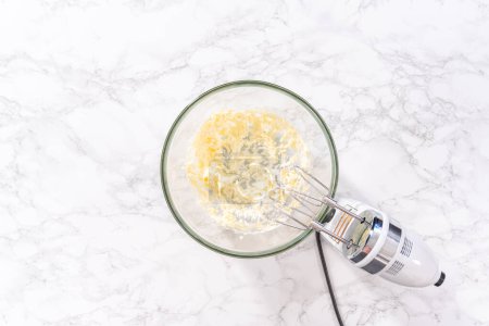 Photo for Flat lay. Mixing ingredients in a large glass mixing bowl to prepare cream cheese drizzle sauce. - Royalty Free Image