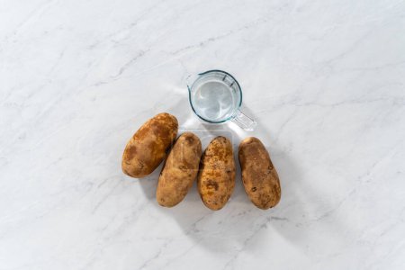 Foto de Flat lay. Pressure Cooker Baked Potatoes. Measured ingredients on the kitchen counter to prepare baked potatoes. - Imagen libre de derechos