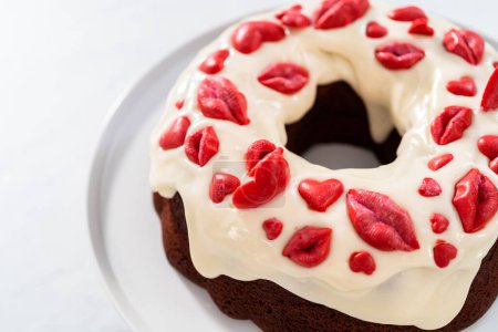 Photo for Freshly baked red velvet bundt cake with chocolate lips and hearts over cream cheese glaze for Valentines Day. - Royalty Free Image
