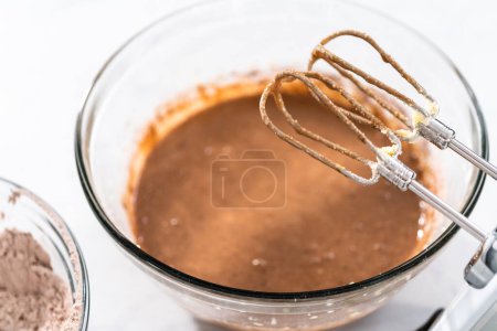 Photo for Mixing ingredients in a large glass mixing bowl to bake red velvet bundt cake with cream cheese glaze. - Royalty Free Image