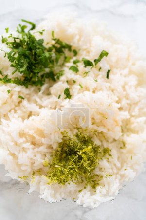 Photo for Cilantro Lime Rice. Mixing ingredients in a glass mixing bowl to prepare cilantro lime rice. - Royalty Free Image