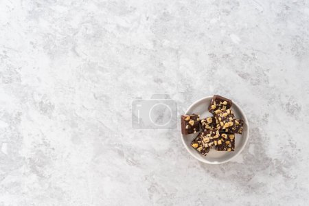 Foto de Acostado. Piezas cuadradas hechas en casa de chocolate avellana fudge en un plato blanco. - Imagen libre de derechos