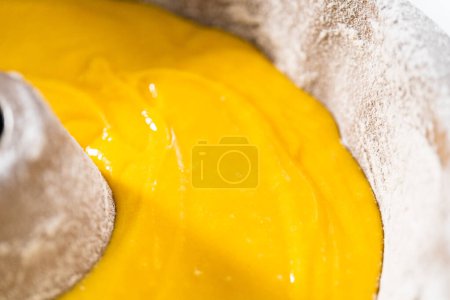 Photo for Pouring cake batter into a greased bunt cake pan to bake a simple vanilla bundt cake. - Royalty Free Image