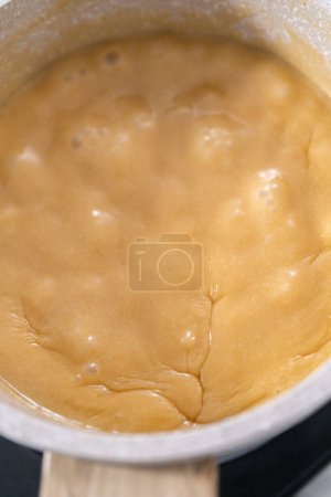 Téléchargez les photos : Préparer la glaçure au caramel dans une petite casserole au-dessus d'une cuisinière électrique. - en image libre de droit